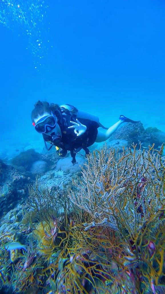 A happy diver giving the okay sign with the hands as they learn on the course before diving