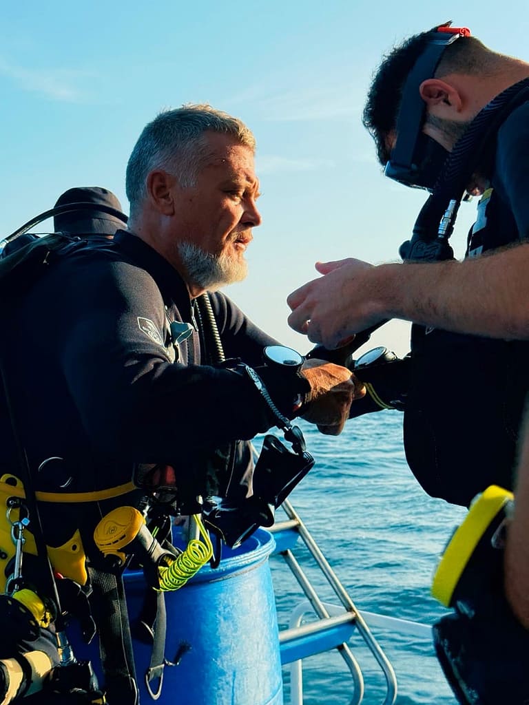 A scuba diving instructor gearing up his students with before going for a diving experience.